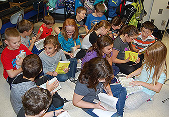 students sit on floor reading their new dictionaries