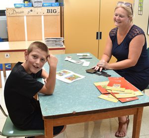 student sitting at classroom table with teacher