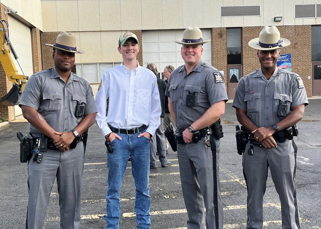 A student stands with three state troopers
