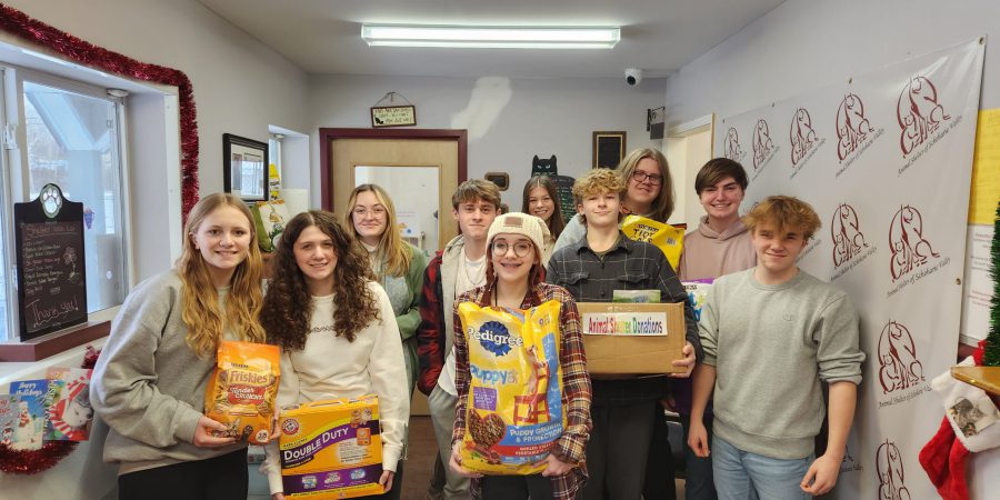 12 students stand with donations for an animal shelter