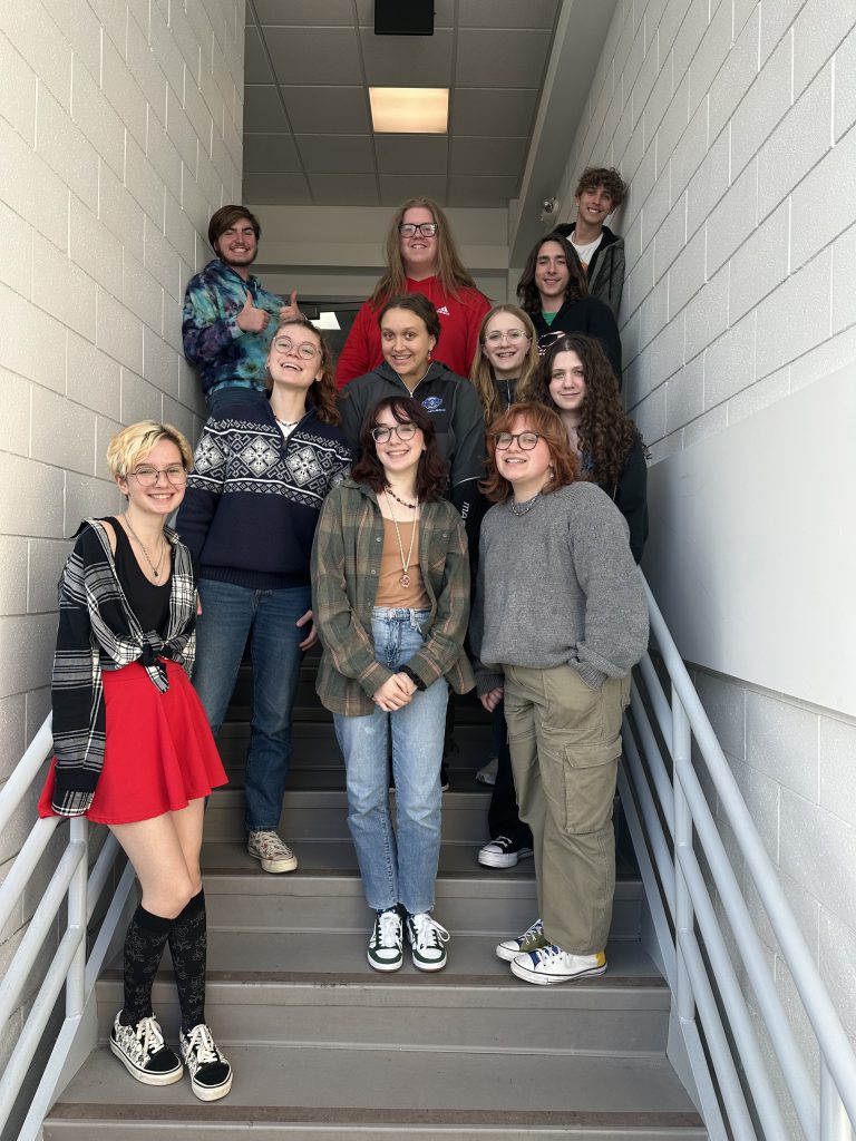 11 students stand on stairs