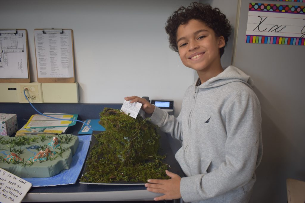 A student displays a landforms project