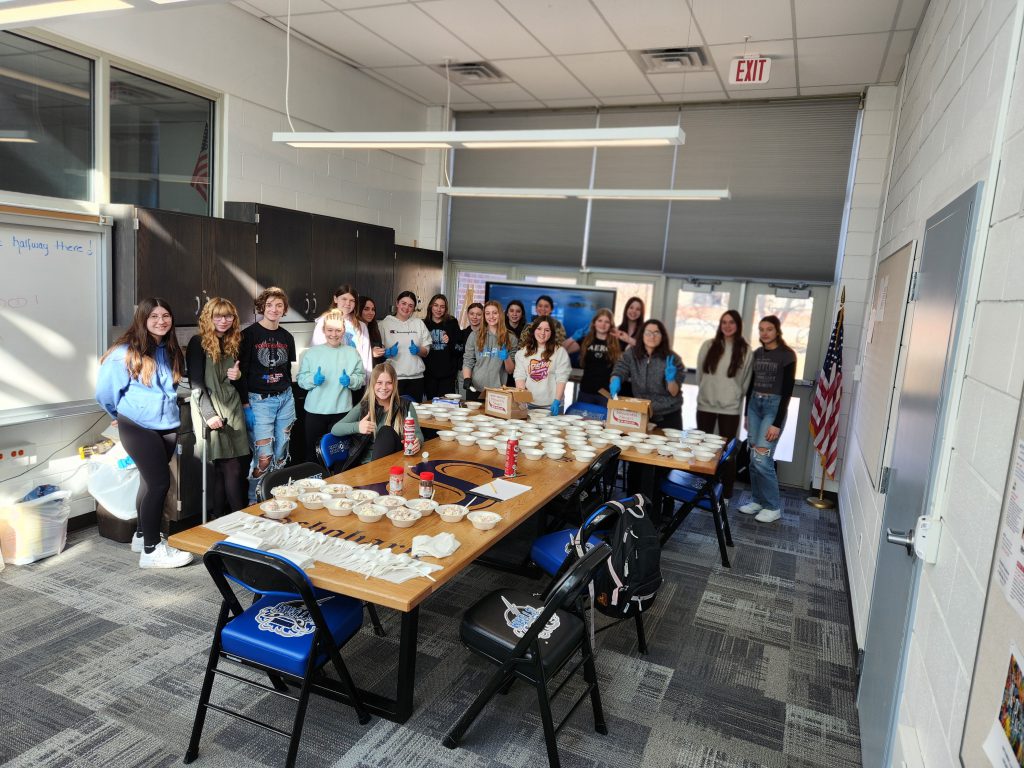 Students stand behind a table