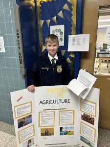 A student holds an agriculture poster board