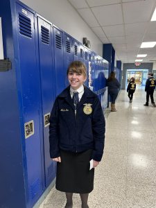 A student stands next to lockers