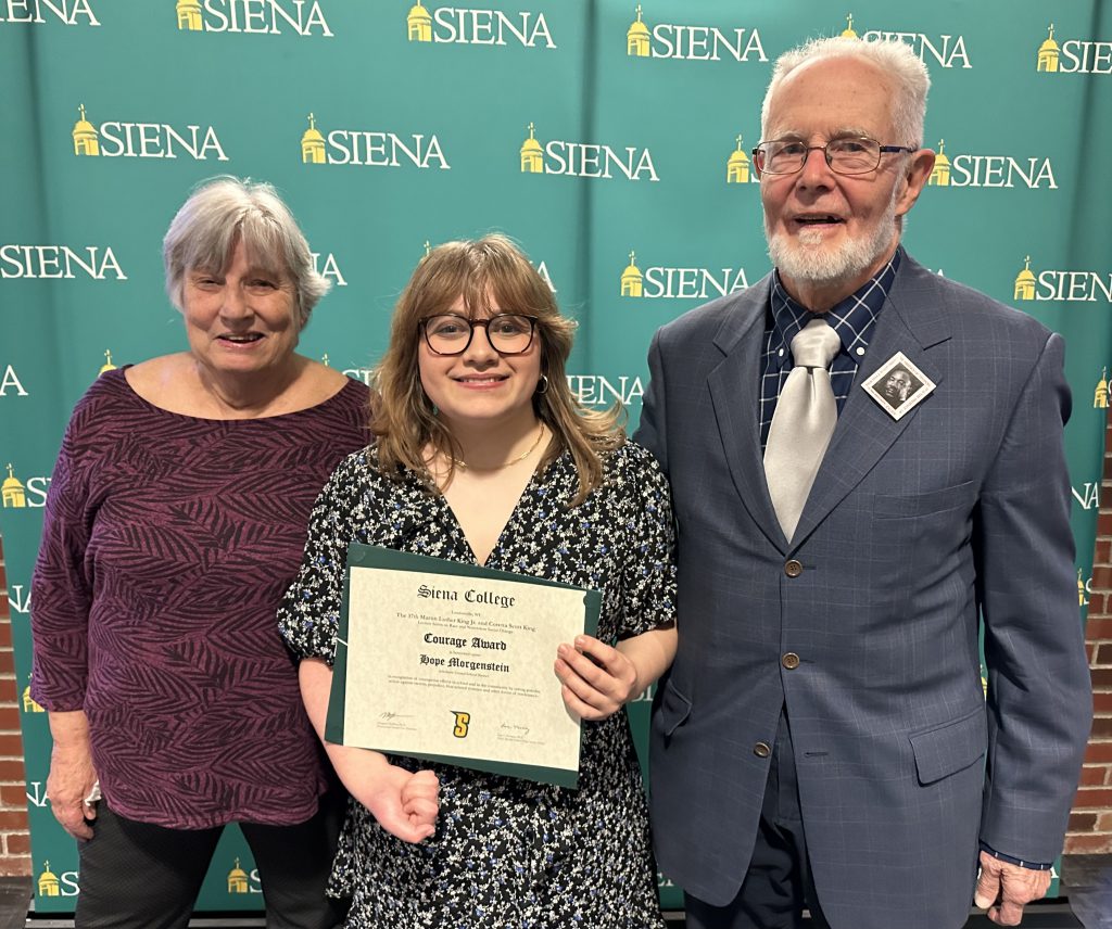 a student stands with two adults