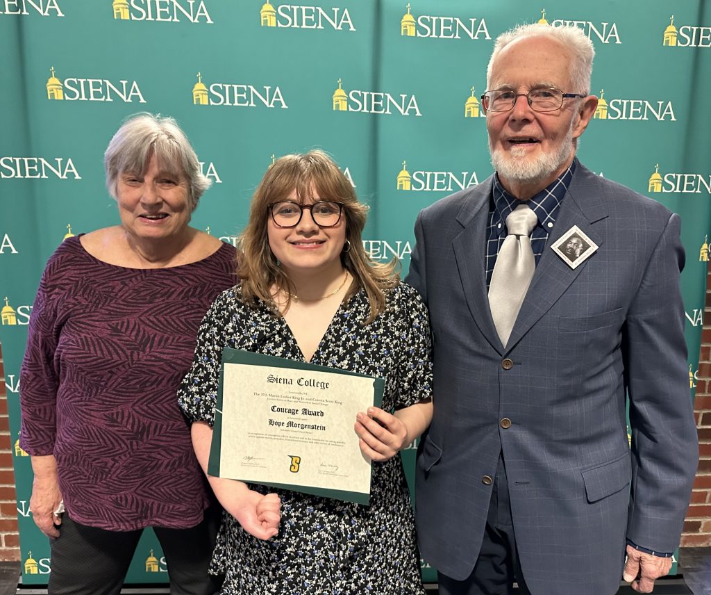 a student stands with two adults