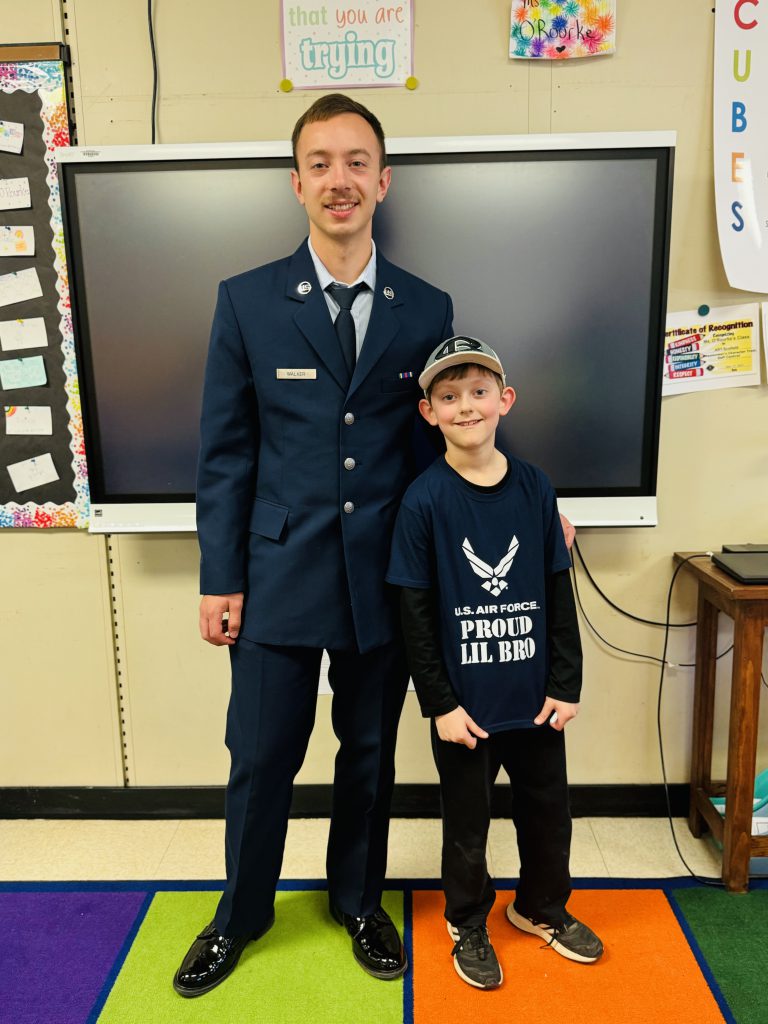 A student stands next an airman