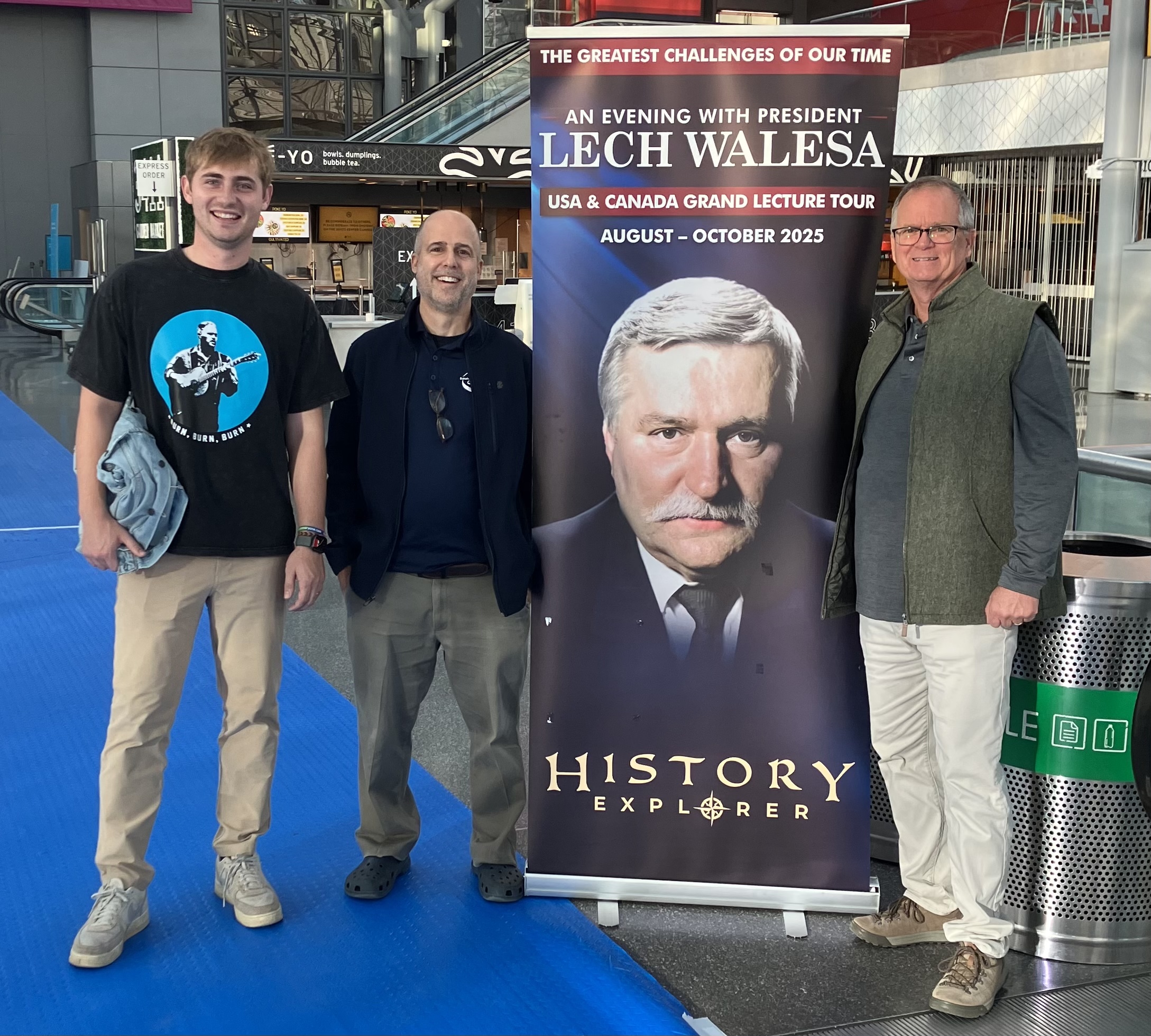 Three people stand next to a poster