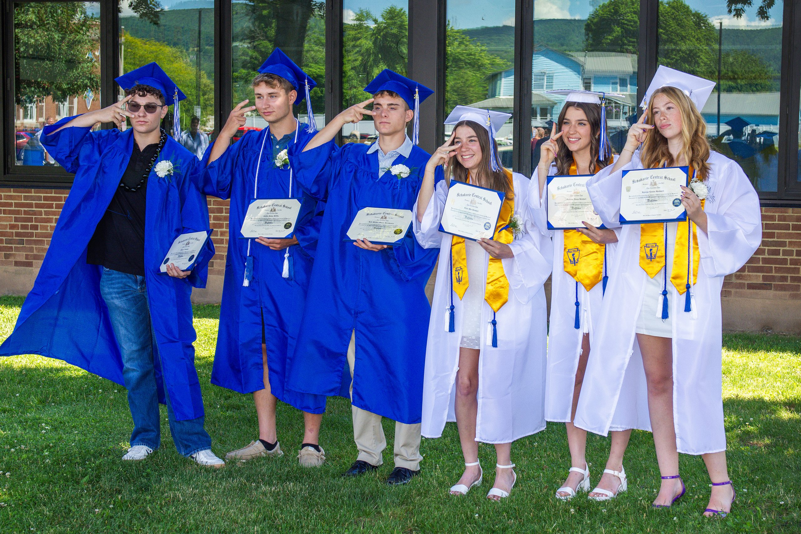Students stand with diplomas