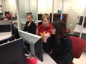 Three students work at a computer