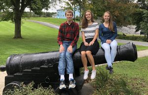 Jedidiah Fox, Jacqueline Gerstenberger and Madeline Phelan sit on cannon in front of school