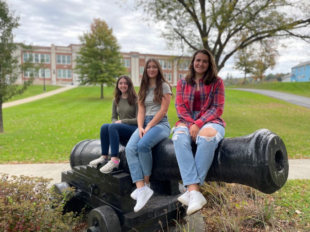 Three students sit on a cannon