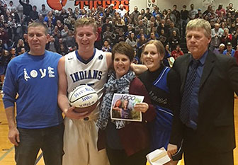basketball star stands with his parents and coach