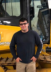 Alex Cipperly standing in front of heavy equipment