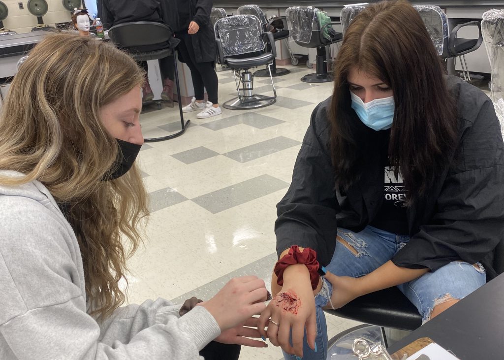 Two students work on makeup