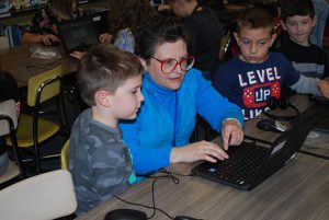 librarian types on laptop as two elementary students listen