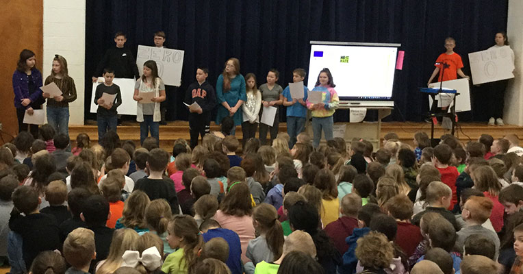 5th graders standing on stage reading their poems
