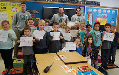 siena players work in classroom with kids