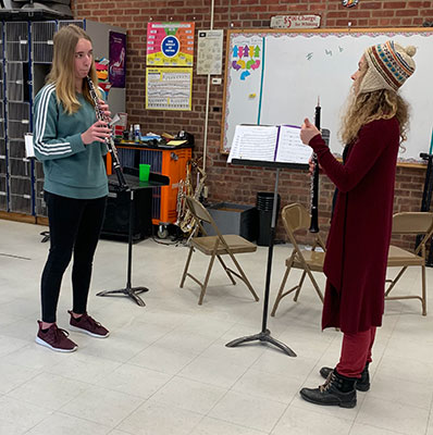 adult teaches female student on oboe