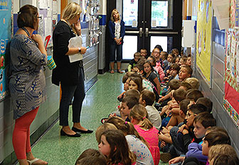students sit on hallway floor listening to teacher