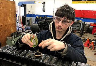 student works on a car engine