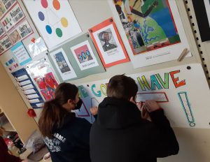 Two students draw on a poster