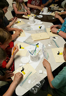 students work at a large table on a bee activity