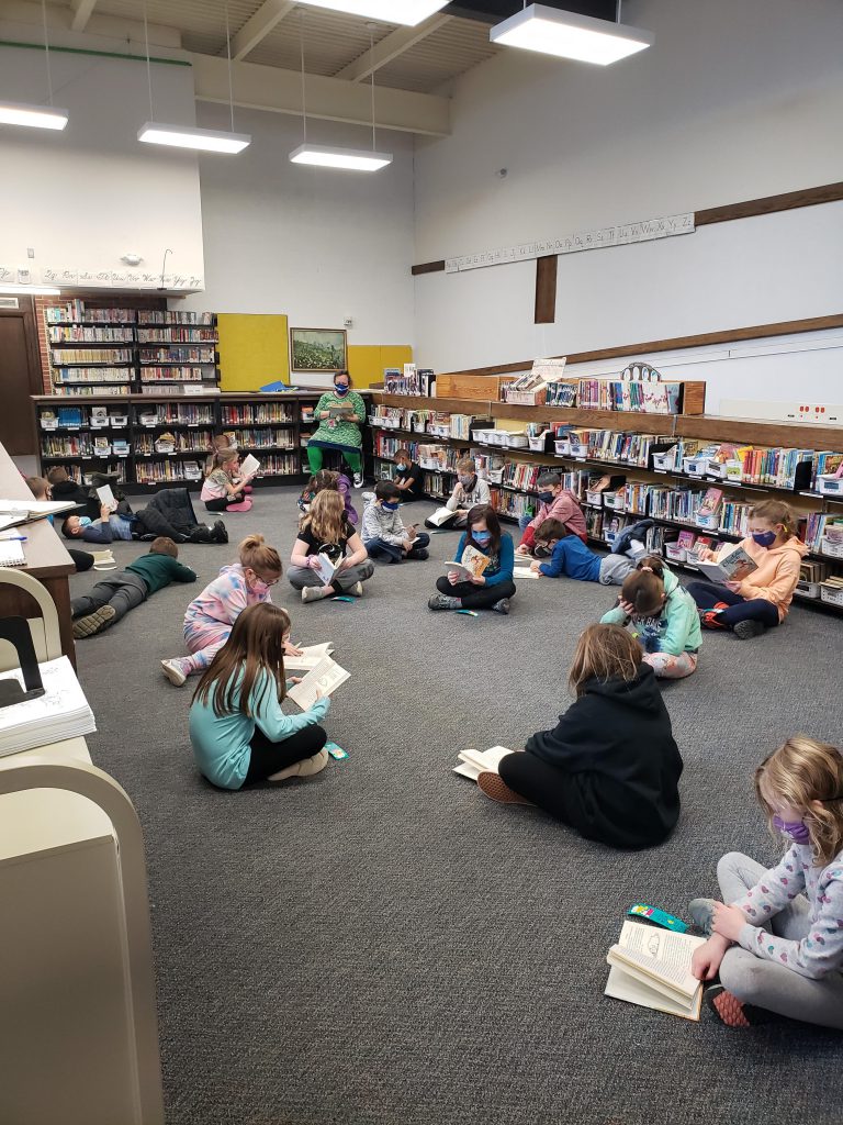 A class sits on the floor of a library