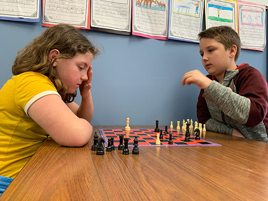 girl and boy playing chess