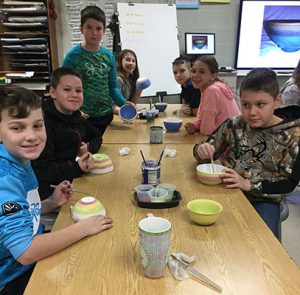 students at tables painting bowls