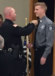 Officer Minton puts pin on shirt of Fletcher Griffin