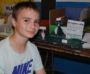student poses next to water body model he created
