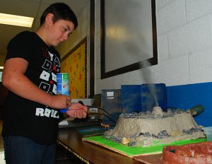 student shows how his model geyser erupts steam