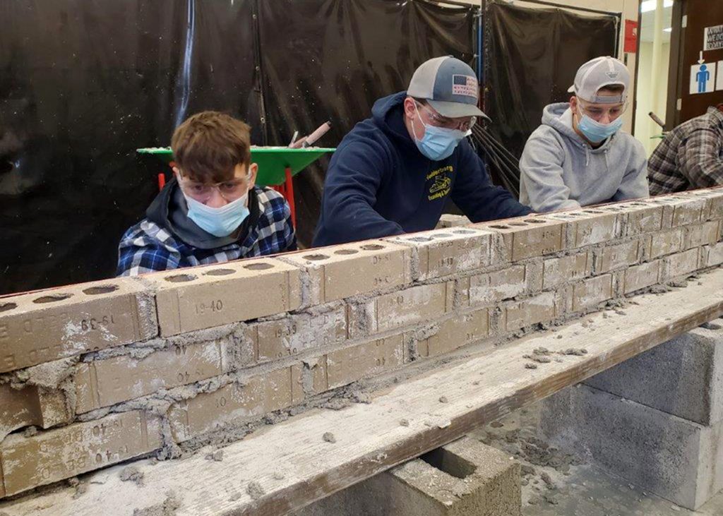 Three students work on bricks