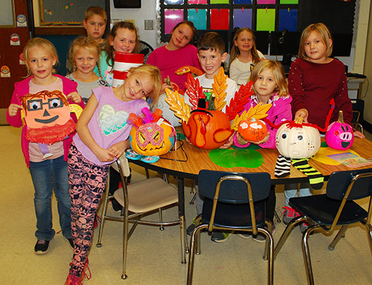 boys and girls standing near pumpkins