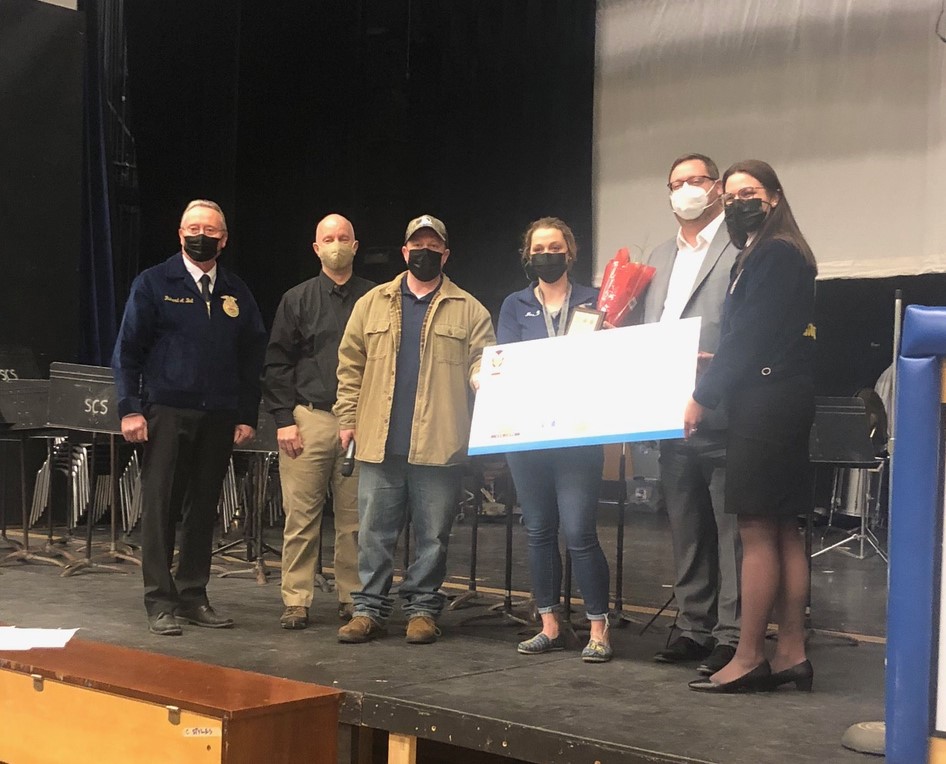 six adults stand with a check