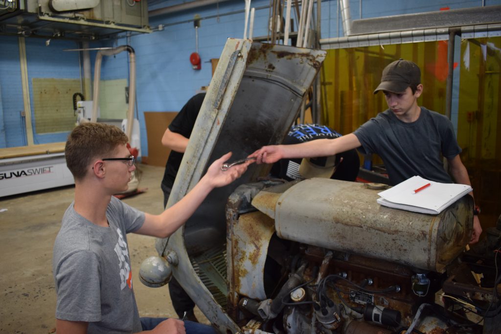 Three students work on a tractor